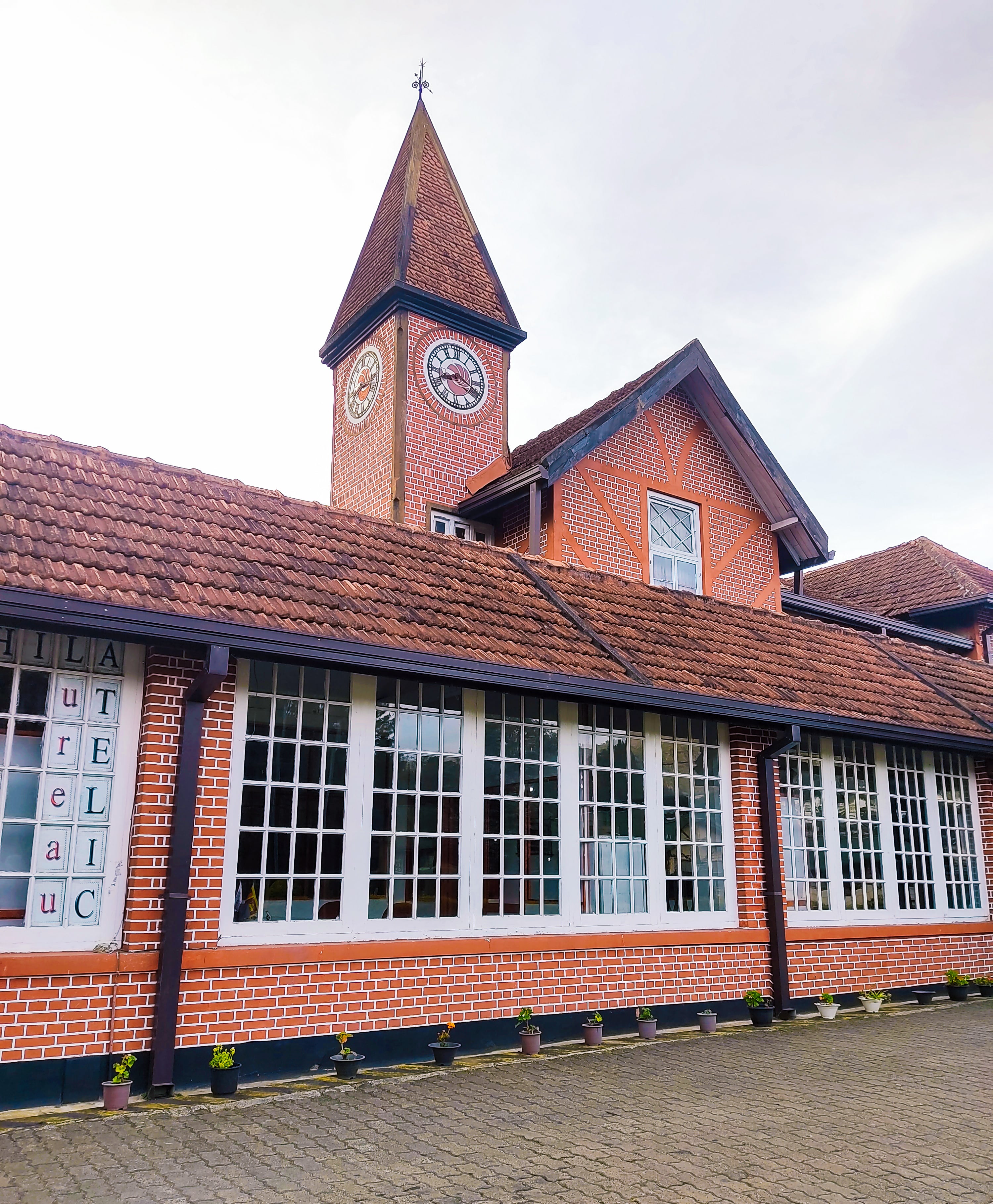 The iconic red-brick Nuwara Eliya Post Office with its prominent clock tower against an overcast sky.